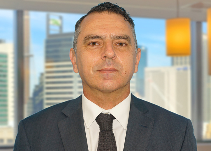 A photo of Chris Balalovski looking straight ahead with a view of Sydney in the background