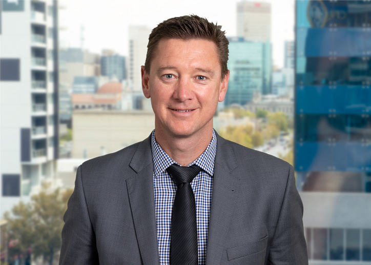 A photo of Tim Kelly looking straight ahead with a view of Adelaide in the background